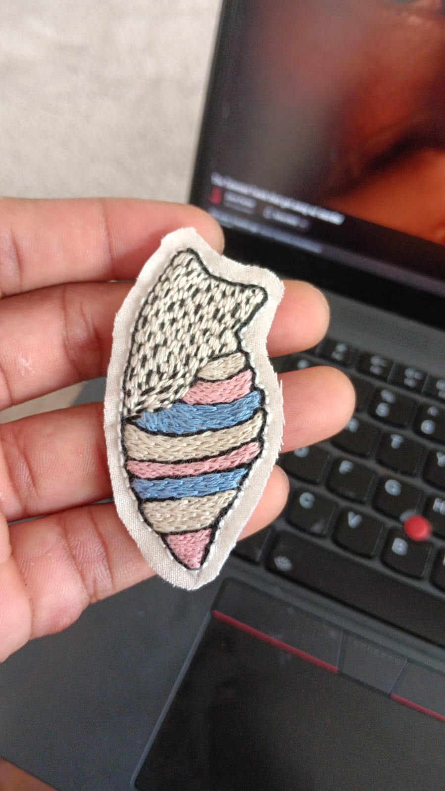 Image of an embroidered patch of a cocoon in white, pink and blue