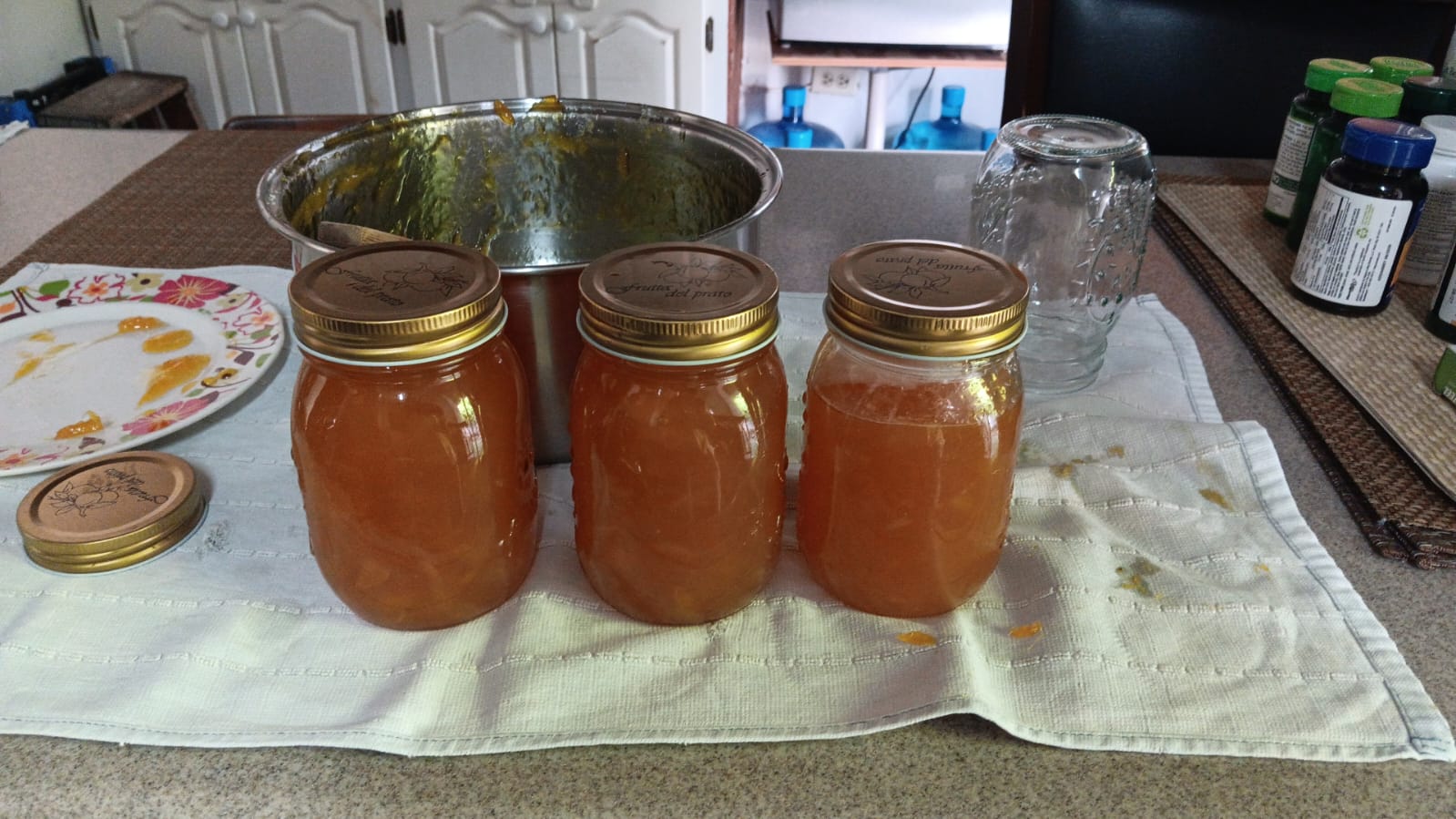 A picture of three jars of bright orange mango jam, 2 of which are completely full, the last of which is only about half full